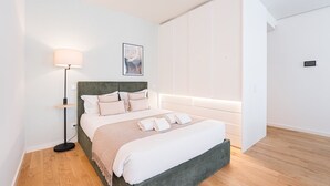 A modern bedroom with a bed, bedside lamp, and a wall-mounted light. - GuestReady - A marvellous city retreat (Porto)