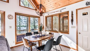 A dining area with a wooden table, black chairs, and a hanging light fixture.