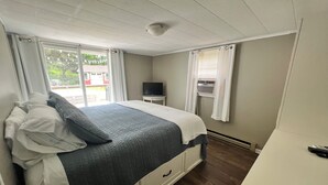 Een slaapkamer met een bed, een televisie en een raam met gordijnen.