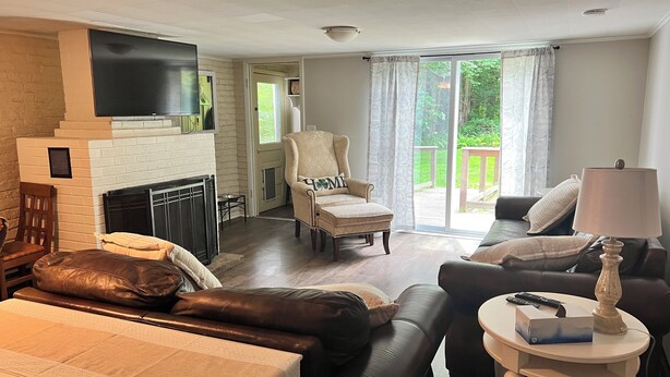 Een woonkamer met een open haard, een bank, een fauteuil en een televisie.