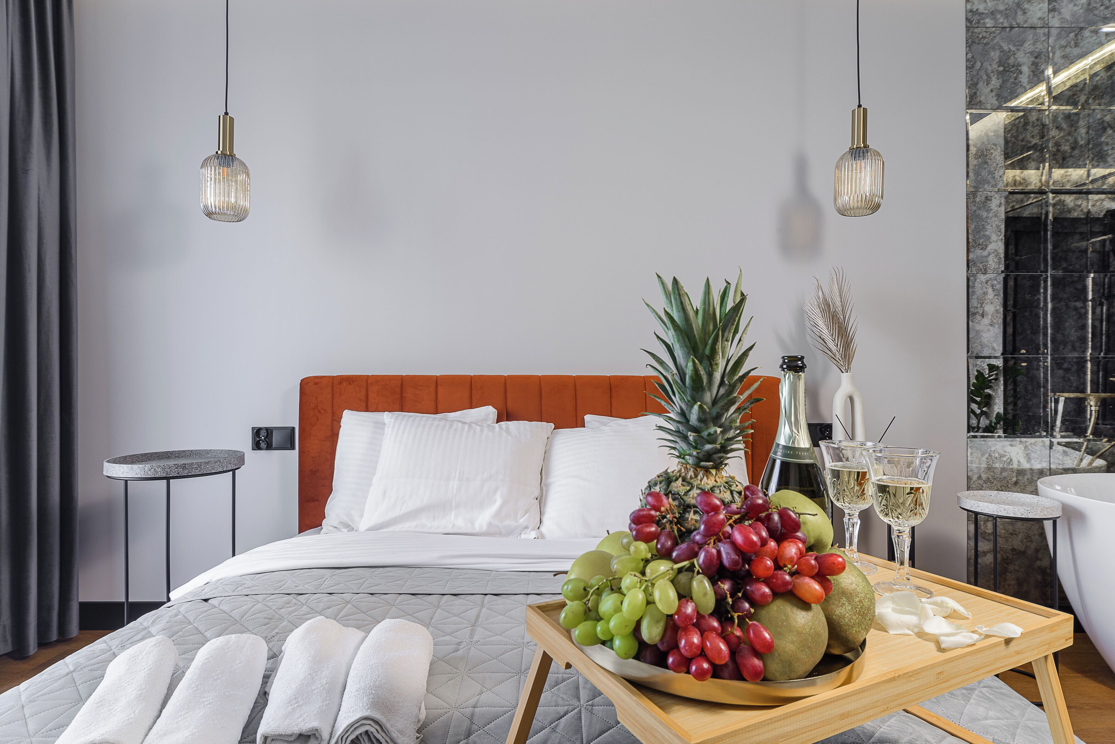 A hotel room with a bed, a fruit tray, towels, and a bathroom with a bathtub.