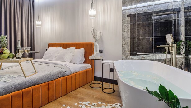 Een moderne hotelkamer met een groot bed, een badkuip en uitzicht op de stad.