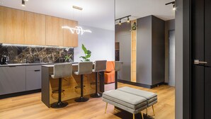 Een moderne keuken met barstoelen, een bank en een marmeren achterwand.