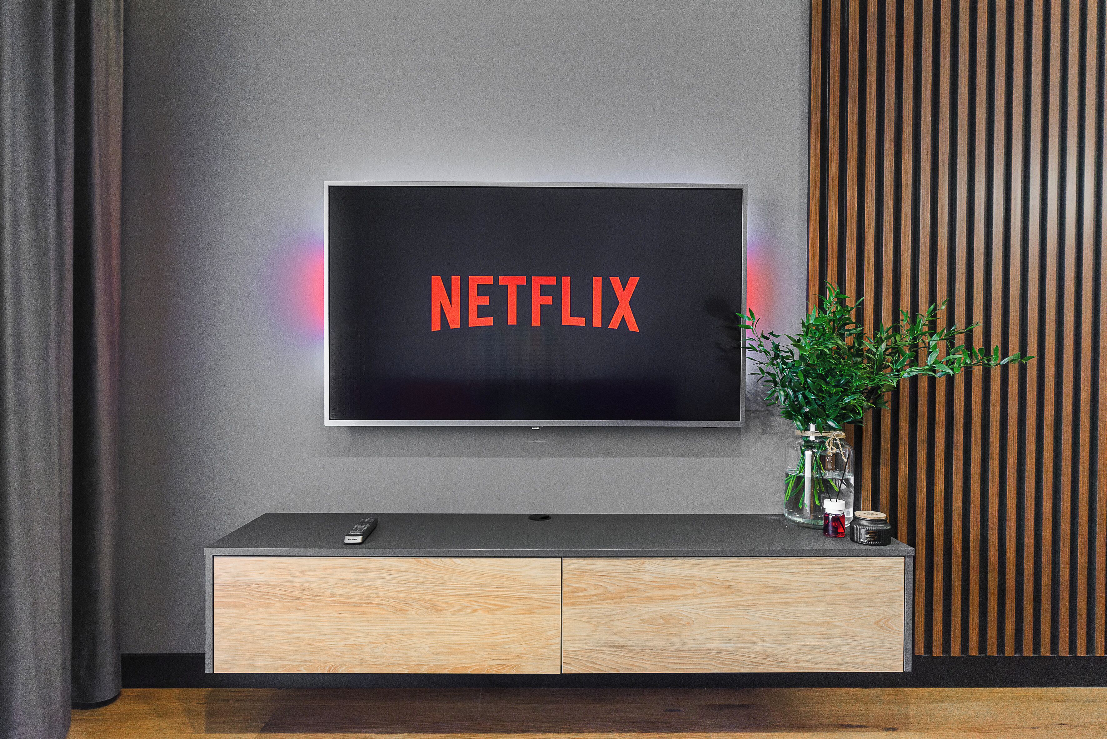 A flat-screen TV mounted on a wall with a wooden cabinet below it.