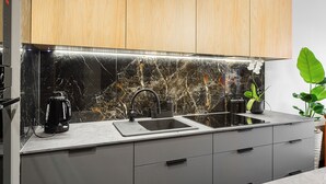 Een moderne keuken met een marmeren achterwand, een zwarte koffiezetapparaat en een plant.
