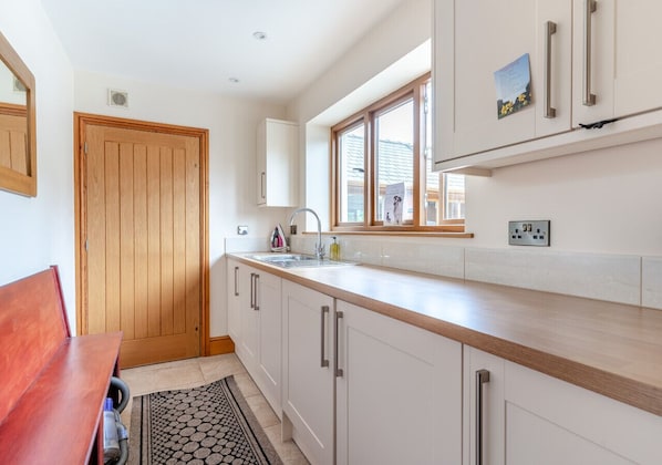 Compact kitchen with white cabinetry, light countertop, and window above the sink.