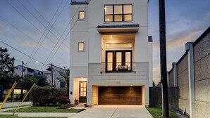 A modern two-story house with a garage, a balcony, and a well-lit entrance. - Houston Home w/ Rooftop Patio - 3 Mi to Downtown!
 (Houston)