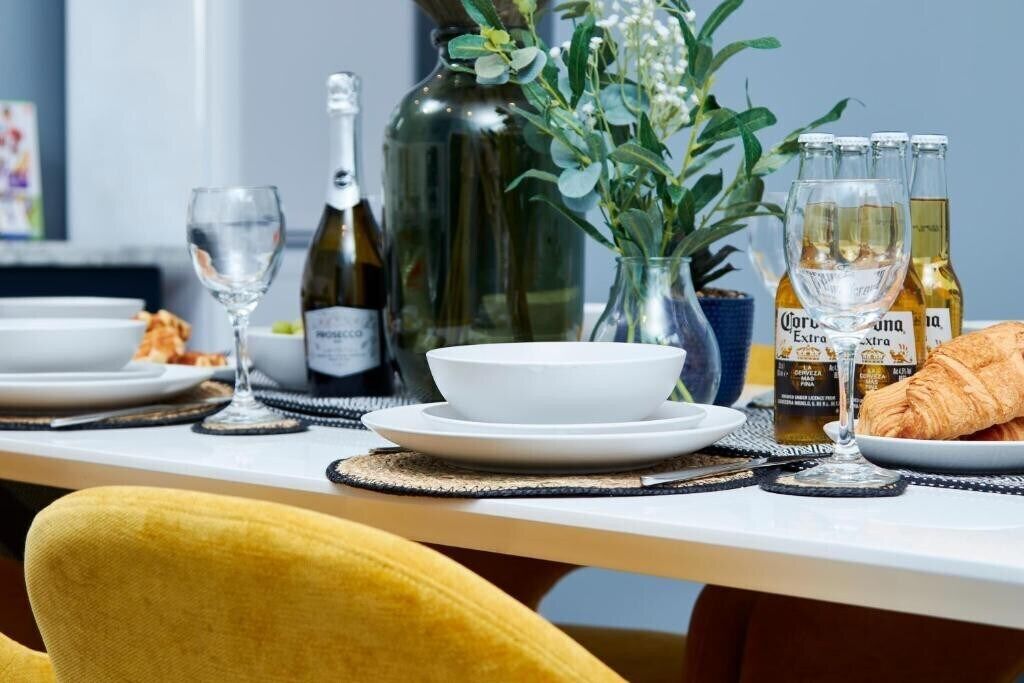 A dining table with a bottle of wine, a glass, a bowl, and a croissant.