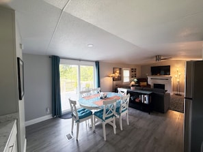 Un amplio espacio habitable con una mesa de comedor, sillas, un sofá, chimenea y televisor.