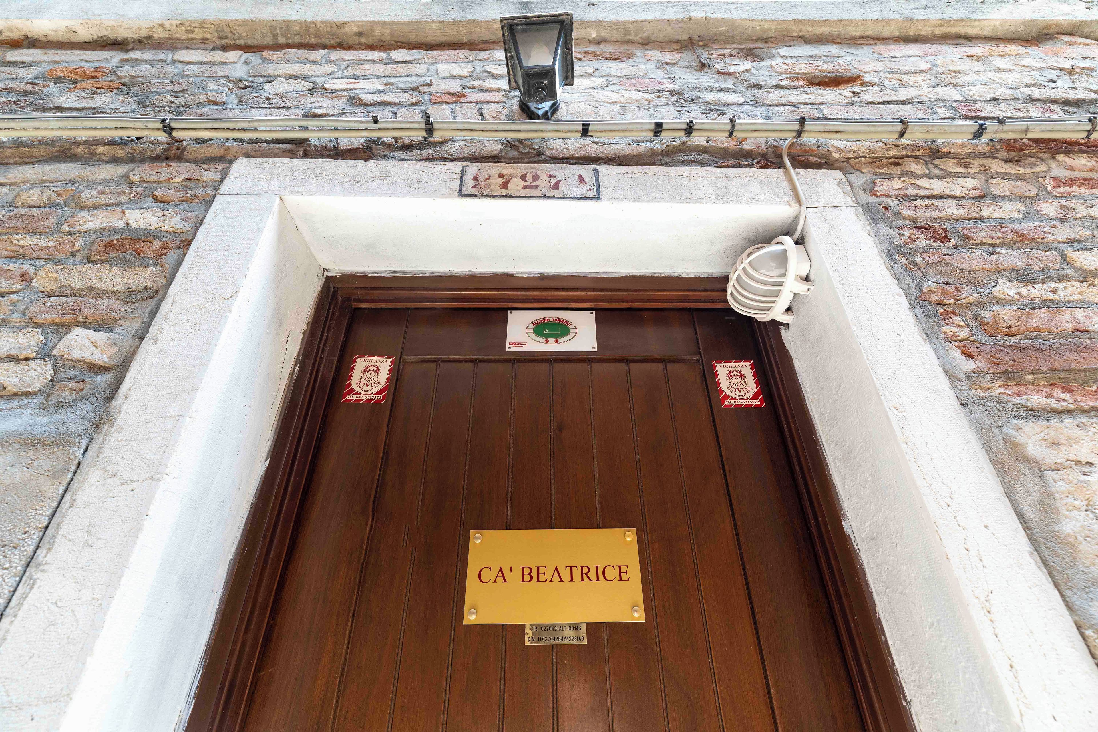 Eine Holztür mit einem Schild, auf dem 'CA' BEATRICE steht, und einem kleinen Wappen darüber.