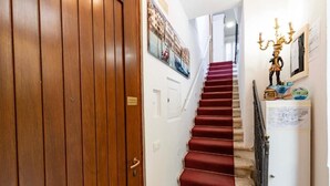 A wooden door, a red carpeted staircase, and a wall with a framed picture and a candelabra. - Ca' Beatrice (Venice)