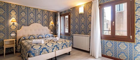 A bedroom with a large bed, two bedside lamps, a radiator, and a window with curtains.