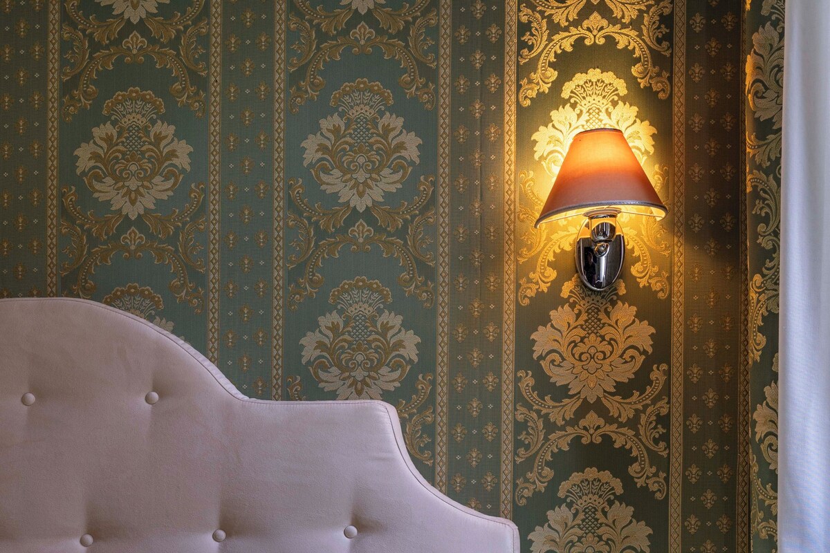 Ein Schlafzimmer mit einem gesteppten Kopfteil, einem Nachttisch und einer Wandlampe.