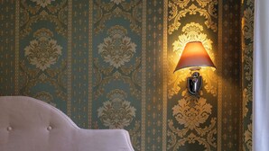A bedroom with a tufted headboard, a bedside table, and a wall-mounted lamp. - Ca' Beatrice (Venice)