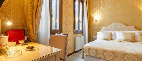 Habitación de hotel con cama, escritorio y silla, cafetera roja y ventana con cortinas.