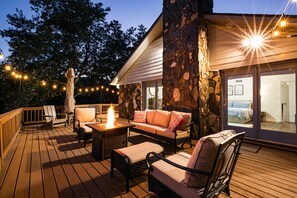 Eine Terrasse im Freien mit Holzboden, Korbmöbeln und einer Steinmauer.
