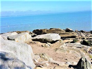 Uma linha costeira rochosa com grandes pedras e vista clara para o mar.