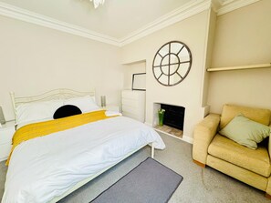 A bedroom with a bed, a sofa, a fireplace, and a decorative wall piece. - Hyperion in Newmarket (Newmarket)