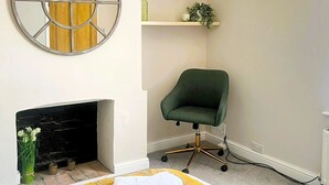 A bedroom with a bed, a green chair, a fireplace, a round mirror, and a shelf with a plant. - Hyperion in Newmarket (Newmarket)