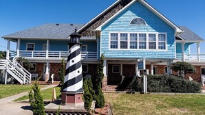 A two-story house with a blue exterior and a black and white striped lighthouse in the front yard. - Gloria - Offshore Beach Club (Buxton)