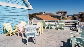 A beachside patio with Adirondack chairs and a table, overlooking the ocean. - Gloria - Offshore Beach Club (Buxton)
