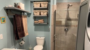 Een badkamer met toilet, douche en planken met handdoeken.