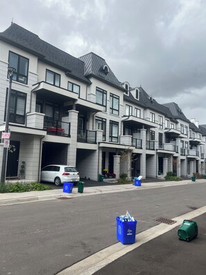 A row of modern multi-story residential buildings with balconies and a garage.