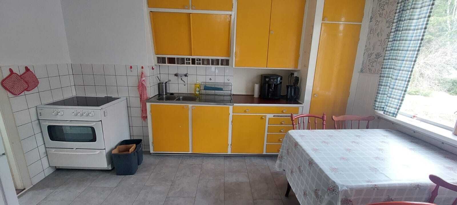 Una cocina compacta con estufa, pileta y armarios amarillos.