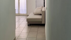 Un couloir étroit, doté d’un sol carrelé, mène à un balcon auquel on accède par une porte coulissante.