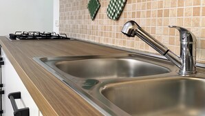 Une cuisine dotée d’un évier en acier inoxydable, d’une cuisinière à gaz et d’un dosseret carrelé.