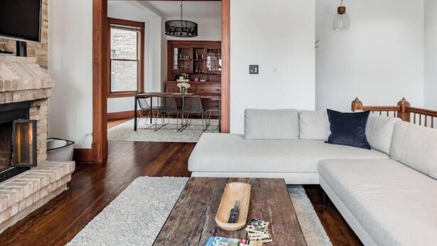 A living room with a fireplace, a sofa, a coffee table, and a dining area with chairs and a table.