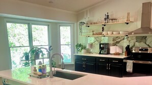Una cocina moderna con una isla grande, taburetes de bar y vistas al exterior.