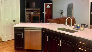 Una cocina moderna con lavavajillas, armarios oscuros, una isla grande, tragaluces y un ventilador de techo.