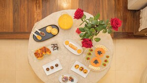 Une table ronde sur laquelle sont disposés divers aliments et un vase de roses rouges.