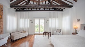 Une chambre avec un plafond en bois, un grand lit, un canapé, une petite table et une lampe.