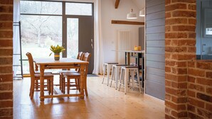 Un comedor con mesa y sillas de madera, una planta en maceta y vistas amplias por grandes ventanales.