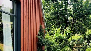 Un edificio moderno con fachada roja, una puerta de cristal y un patio con baldosas.