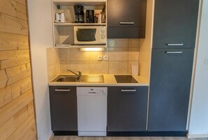 A compact kitchen with a microwave, coffee maker, and dishwasher.