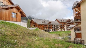A cluster of wooden buildings with balconies, set against a mountainous backdrop. - 200m from resort center, 3rd floor, swimming pool, tv, ski locker, 23m², Les Orres (Les Orres)