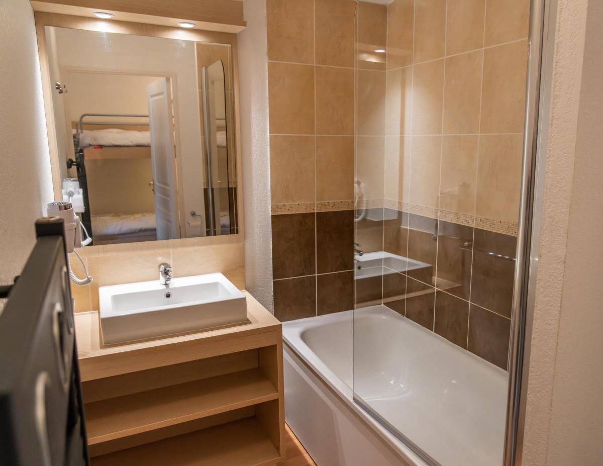 A bathroom with a sink, mirror, and bathtub.