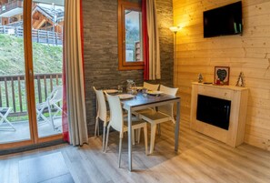 A dining area with a table and chairs, a fireplace, and a television mounted on the wall.