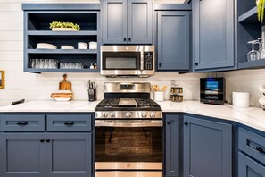 Una cocina moderna con armarios azul oscuro, electrodomésticos de acero inoxidable y un horno empotrado.