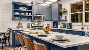 A modern kitchen with a central island, built-in appliances, and a window with a view of greenery. - Family Retreat | Perfect Location | Hot Tub (Broken Bow)