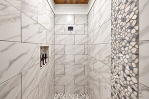 A shower with a marble wall and a pebble mosaic.