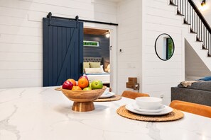 Un interior moderno con una mesa de comedor de mármol, un frutero y una zona de estar acogedora.