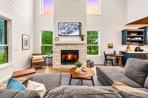 Amplia sala de estar con chimenea, comedor y cocina con gabinetes azules.