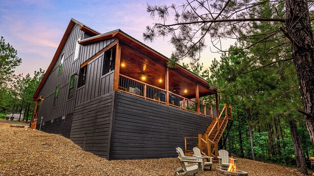 A cabin with a wooden exterior, a balcony, and a fire pit area. - Family Retreat | Perfect Location | Hot Tub (Broken Bow)