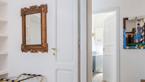 A hallway with a gold-framed mirror, a drying rack, and a door leading to a bathroom. - Trastevere novecento (Rome)