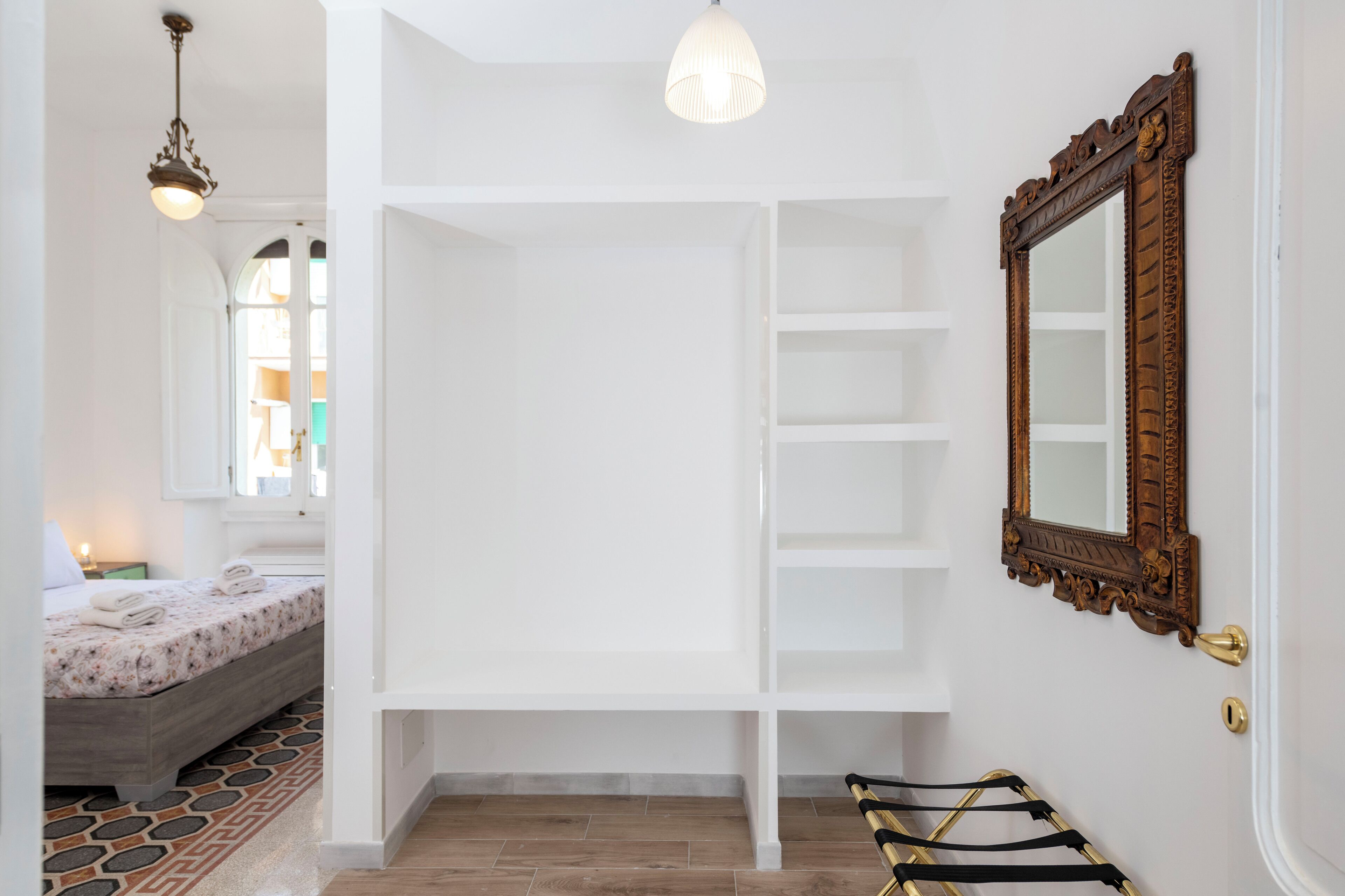A bedroom with a bed, a wardrobe, a mirror, and a hanging rack.