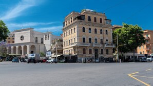 A street view with buildings, vehicles, and a clear sky. - Trastevere novecento (Rome)